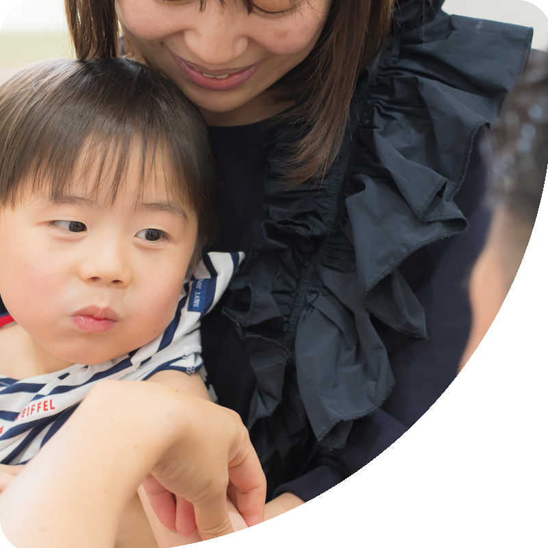 お母さんに抱かれて予防接種を受けるお子さま