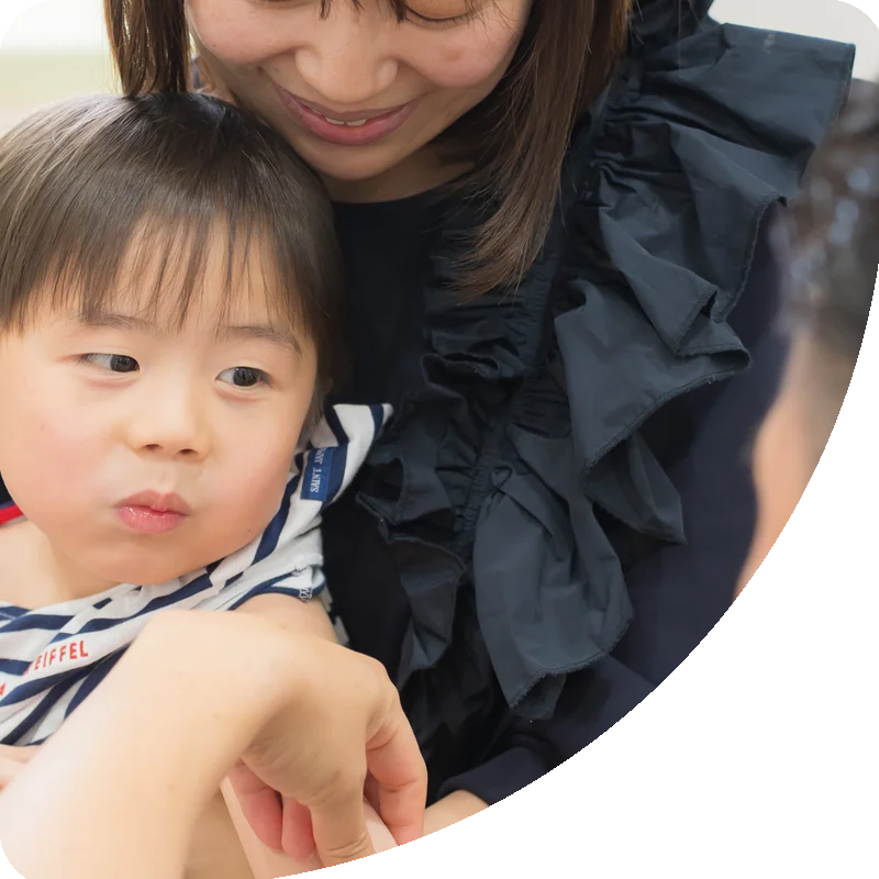 お母さんに抱かれて予防接種を受けるお子さま